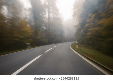 Long exposure, blurry autumn morning covered empty rural road through a forest in Europe. Wide angle view, limited visibility, bad driving weather concept, no people - Powered by Shutterstock