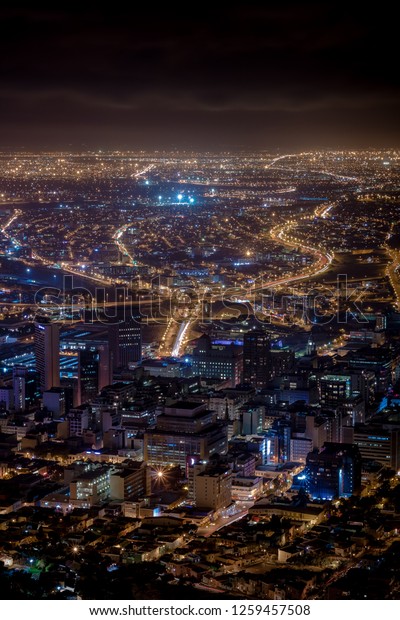 Long exposure of Cape Town city center from above\
at Signal Hill at night showing light trails from cars and vehicles\
on the roads