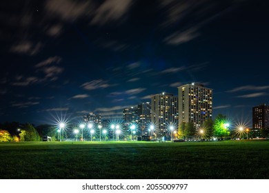 Long Exposure Of Clouds Moving Across A Dark Blue Sky At Night Over Residential Skyscraper Buildings As Bright Lights Shine On Tennis Courts In The Lakeview Neighborhood Lake Shore Drive In Chicago.