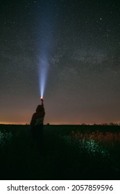 Long exposure dark night photo of man with flashlight on Milky Way and stars constellation. Concept image of new discoveries and aventures