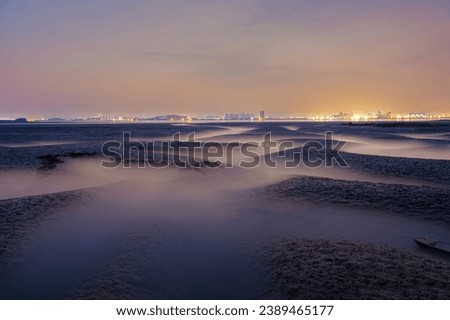 Long exposure and dawn view of mud flat and tidal channel at low tide against light at Yeongjongdo Island near Jung-gu, Incheon, South Korea
