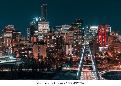 Long exposure of the Edmonton Alberta city skyline at night. The illuminated Walterdale bridge is in the foreground. Vehicle traffic is visible in the light streaks. Blue and Orange tones.