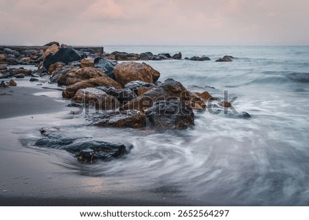 A long exposure effect of ocean waves hitting the sandy beach with stones