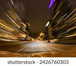 Long exposure fast speedy city drive at roads and highway. City roads in downtown and glittering rainy streets. Diffused foggy lights of the buildings as colourful light trails. Front windshield view.