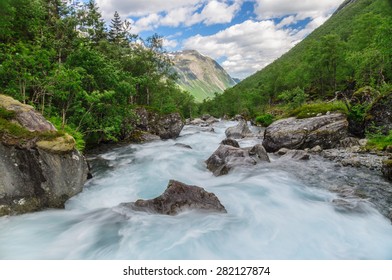 Long exposure flowing rapid mountain river in norwegian sunny valley