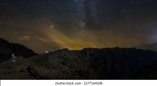 Long Exposure. Giant Volcano With Astronomical Observatory Under The Bright Stars. Milky Way Galaxy On The Darky Orange Purple Mountain Sky. Towers And Domes Of Telescopes Are Aimed At Celestial.