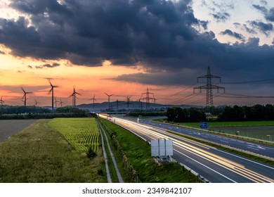 Long exposure of the highway, light trails, sunset, wind turbines and electricity pylons - Powered by Shutterstock