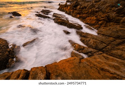 Long exposure image of Dramatic sky seascape with rocks and waves crashing on seashore in sunset or sunrise scenery background