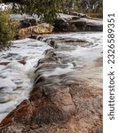 Long exposure image of a small rapids flowing over a rocky ledge