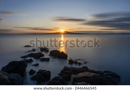 Long exposure image of sunrise over the top of Rangitoto Island. Takapuna Beach. Auckland.