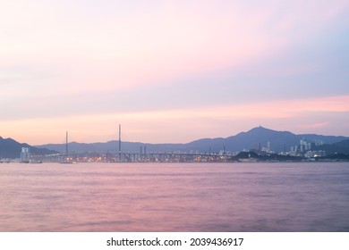 long exposure of landscape with buildings in the New Territories seen from Victoria Harbour along water front in Hong Kong Island during sunset