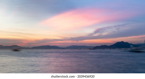 Long Exposure Of Landscape With Buildings In The New Territories Seen From Victoria Harbour Along Water Front In Hong Kong Island During Sunset