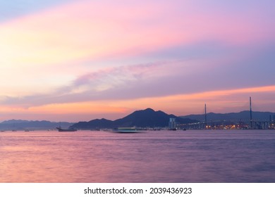 long exposure of landscape with buildings in the New Territories seen from Victoria Harbour along water front in Hong Kong Island during sunset