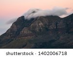 Long exposure landscape photo of a rocky mountain with clouds partially covering the peak at sunset. Pictured : Devil