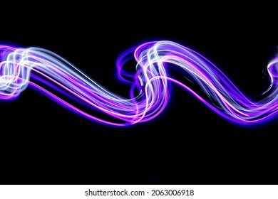 Long exposure light painting photography. Abstract pink purple swirls in a parallel lines pattern against a black background.