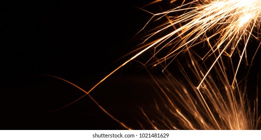 A Long Exposure Macro Shot Showing Fragments Of Burning Magnesium Falling Onto A Black Reflective Surface.