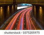 Long exposure of a motorway traffic at night - light trails painted in the shot with a subway station in the background. 