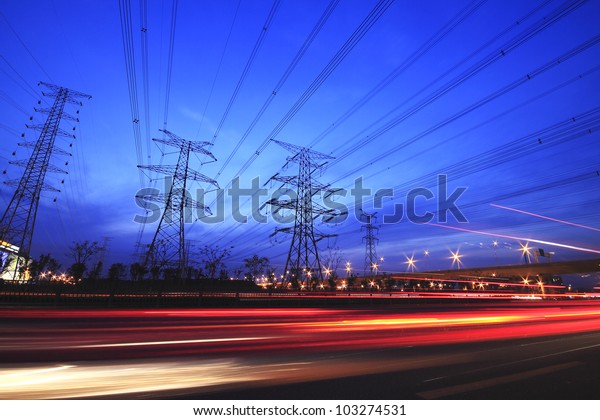 long exposure of\
night car rainbow light traffic on a highway and transmission tower\
at night skyline