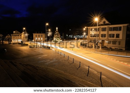 long exposure night image of a roundabout with car light trails and in the center a big illuminated christmas tree
