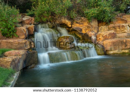 A long exposure photo to induce motion-blur of a man-made waterfall in Frisco's Central Park in Texas.