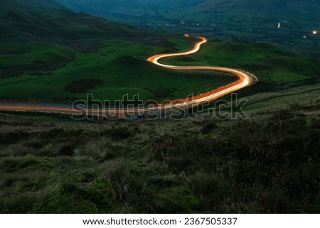 A long exposure photograph of a winding road with car light trails