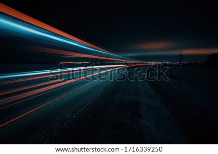 Long exposure of a road with light trails of passing vehicles, glowing sky