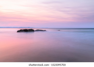 Long Exposure Of Rocks In The Ocean During Sunset On A Cloudy Day In Snapper Rocks, Queensland, Australia.