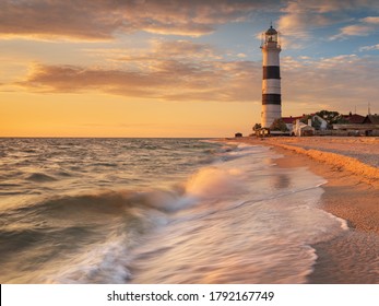 Long Exposure Of Sea Water In View To  Lighthouse In Golden Hour At Sunset