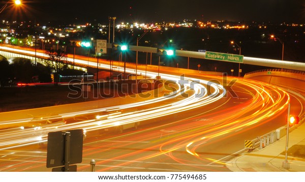 Long exposure shot of busy highway with cars\
driving by, at night.