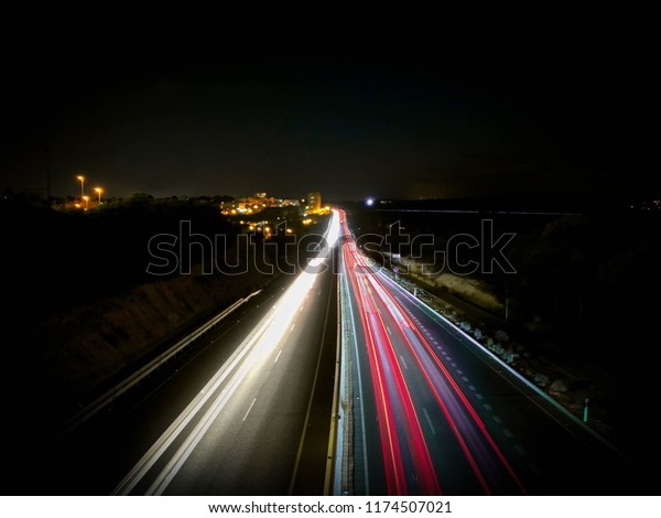 Long exposure shot of a high way at night against\
cityscape. 