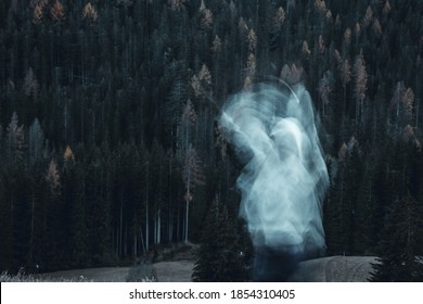 Long Exposure Shot Of Subject In Movement, Creating A Ghost Or Spirit Or Ectoplasm Appearing Just Outside A Thick Forest. Spooky Atmosphere.