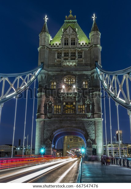 Long exposure shot of Tower Bridge with motion blur of\
walking people,Car and bus traffic light trails on Tower Bridge in\
London at night during the blue hour, London Tower Bridge England\
UK