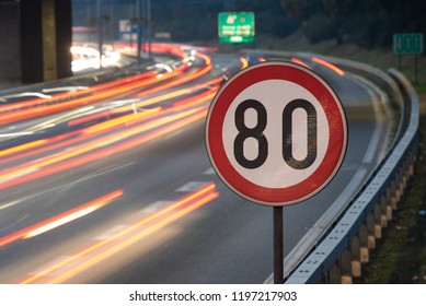 Long exposure shot of traffic sign showing 80 km/h speed limit on a highway full of cars in motion blur during the night - Shutterstock ID 1197217903