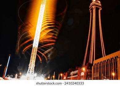 Long exposure of a spinning carnival ride at night with illuminated trails against a dark sky.