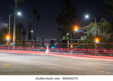 Long Exposure Of A Street In Los Angeles At Night With Light Trails From Automobiles.  Red, Yellow, And Green Lights Appear At The Same Time On The Traffic Light.