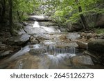 Long exposure and summer view of water and rocks of Okyang Falls in the forest and valley of Songnisan Mountain near Ipseok-ri, Sangju-si, South Korea