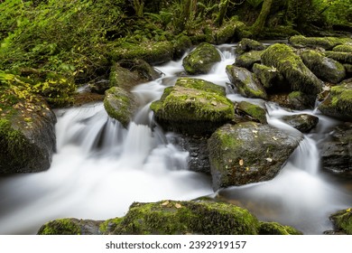 Long exposure of a waterfall on the Hoar Oak Water river at Watersmeet in Exmoor National Park - Shutterstock ID 2392919157