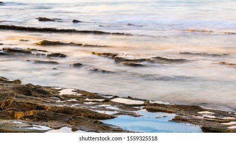 A Long Exposure Of Waves Breaking Onto Rocks At The Seaside Town Of Lorne, Victoria, Australia