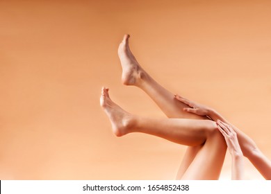  Close up of long female tanned legs with perfectly smooth soft skin, on an orange background. The concept of hair removal, beauty and health. Epilation and hair removal - Shutterstock ID 1654852438
