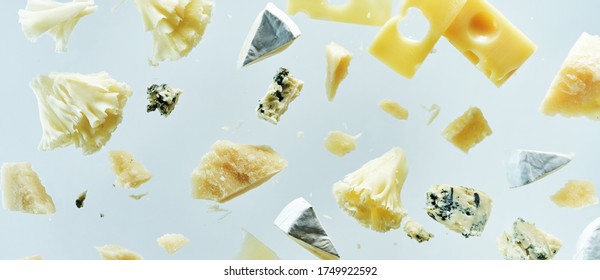 Long food banner with different kinds of cheeses flying in the air with crumbs isolated on white background. Cheeses plate menu. 