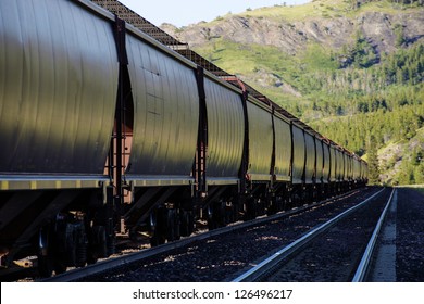 Long freight train with hopper cars parked on railroad siding