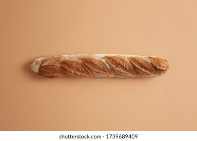 Long French Baguette With Crispy Golden Crust Isolated On Beige Studio Background. Freshly Baked Type Of Bread For Tasty Nutrition. Overhead Shot. Tasty Gourmet Product Baked On Bakery. Food Concept