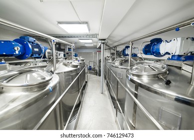 A long gangway between two rows of cisterns. Stainless steel. Storage of food liquids.