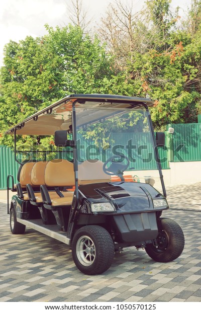 Long Golf Electric Cart At\
The Beach Lift Station On The Paving Road To The Hotel. Black Empty\
Shuttle Eight Seat Electro Car On The Area Near Elevator To Sea\
Beach.