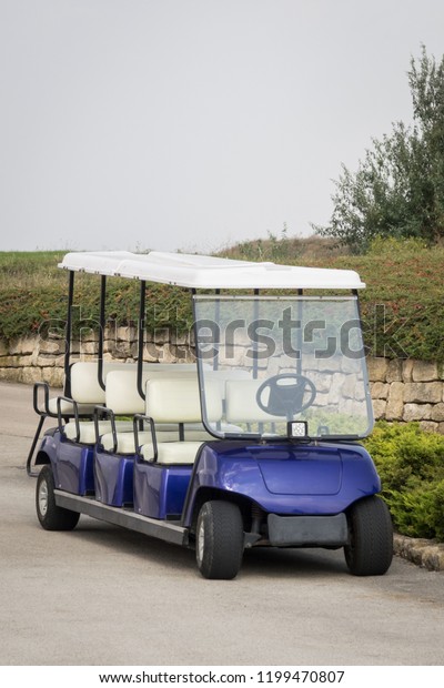 Long golf electric cart parked on parking.\
Empty shuttle eight seat electro\
car