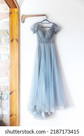 A Long Grey Bridesmaid Dress With Embroidery And Sequins Is On A Hanger On The Wall