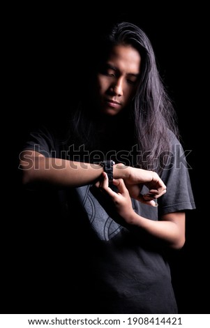 long hair Asian young man portrait using a watch