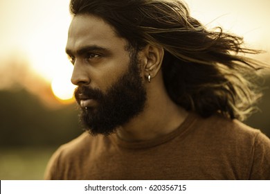 Long Hair Bearded Young Man Portrait Enjoying Breezy Wind In Nature Background. 