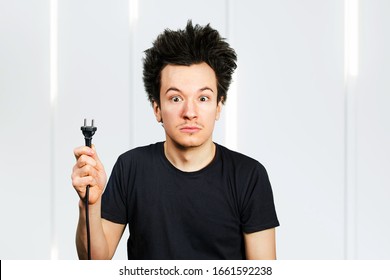 long hair guy holds an electric plug with a cable in his hand on a white background.