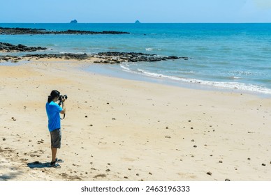 Long hair man wearing backpack take a photo of sea by digital camera on summer beach and blue sky  holiday trip. - Powered by Shutterstock